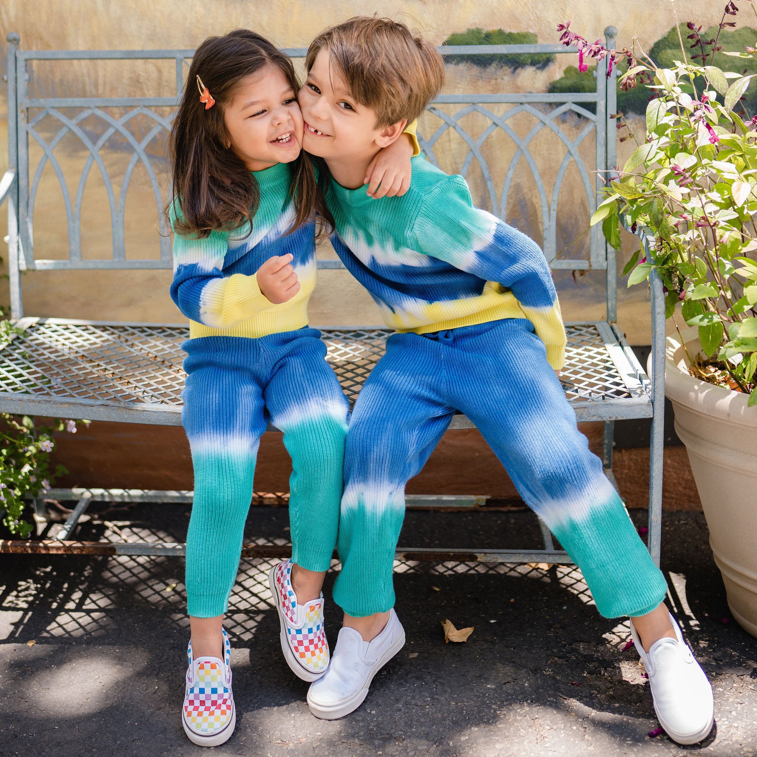 Girl and boy wearing blue and green dip dye knit pants. 