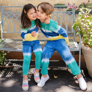 Girl and boy wearing blue and green dip dye knit pants. 