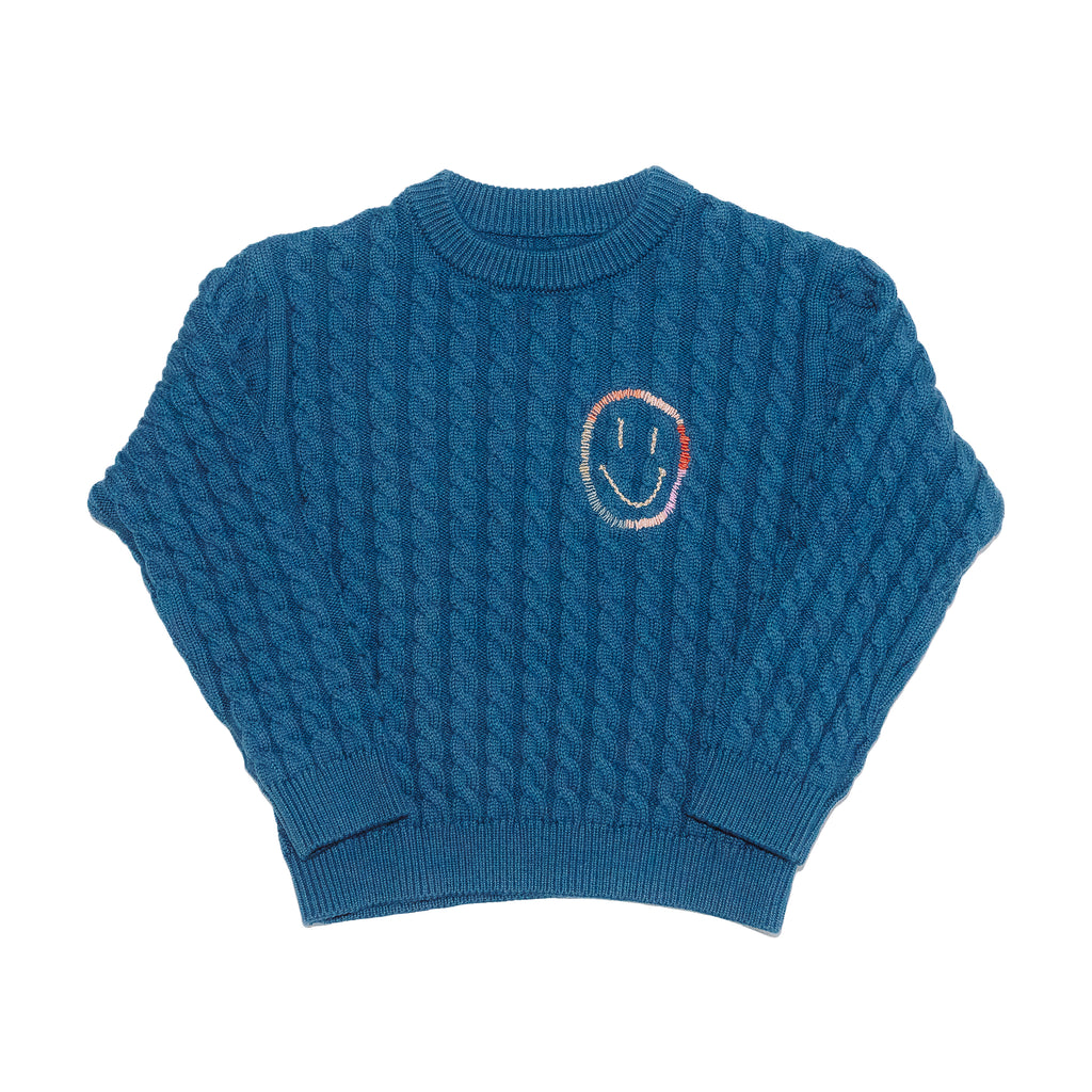 Blue cable knit sweater with happy face embroidery front product shot. 